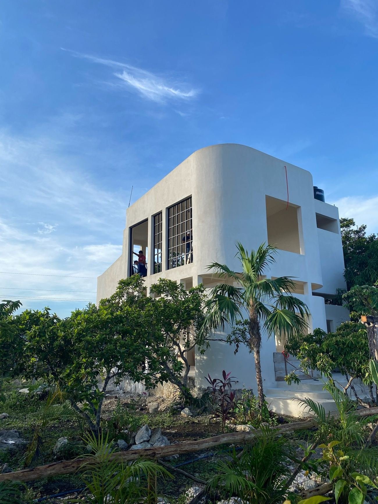 Same round building at Rancho Verde Tulum finished, white stucco exterior with steel-framed windows