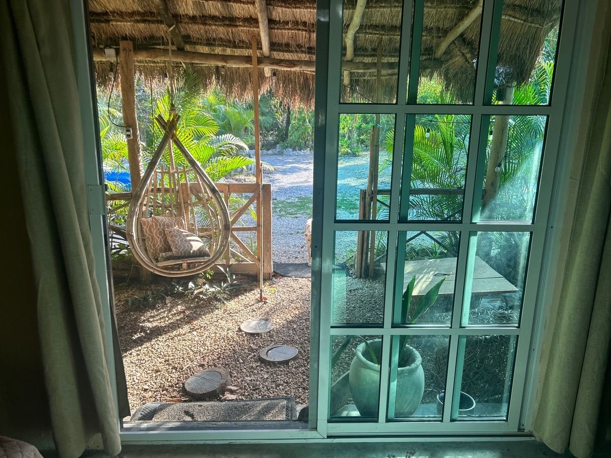 Palapa-roofed porch with hanging chair at Rancho Verde Tulum