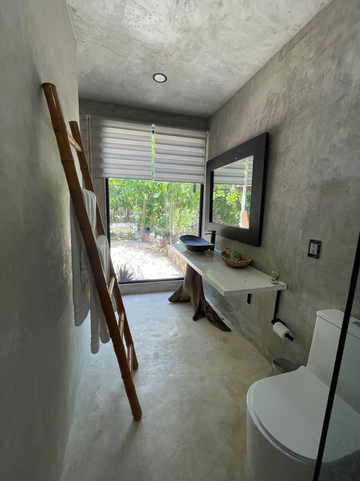 Bathroom with tree-trunk vanity and garden view at Rancho Verde Tulum