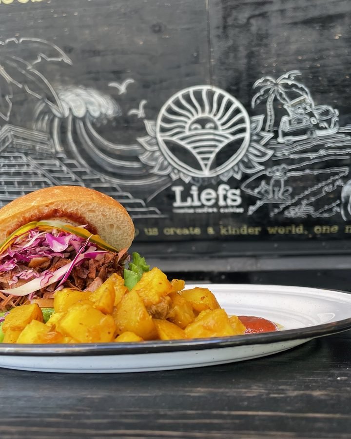 Vegan burger in front of the Liefs chalkboard in Tulum