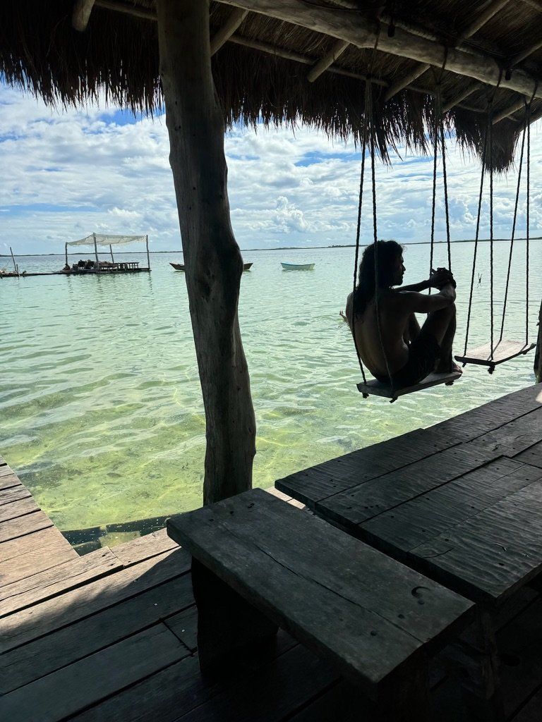Guest reflecting on a jungle swing over the lagoon at Rancho Verde Tulum