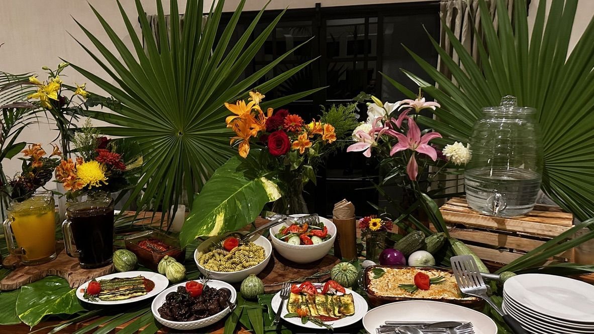 Buffet table with flowers and palm leaves at Rancho Verde Tulum